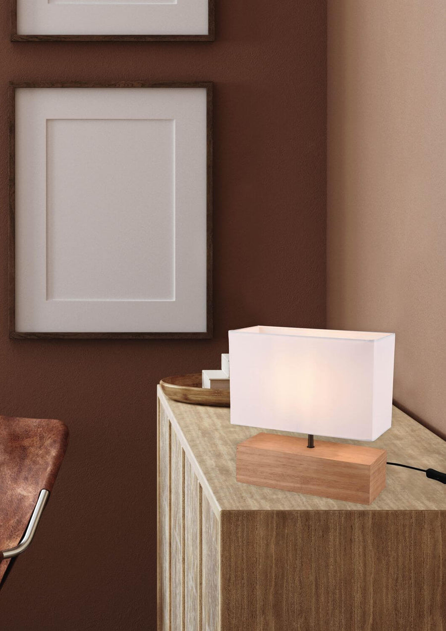 Vue rapprochée de la lampe allumée, abat-jour blanc et socle en bois clair