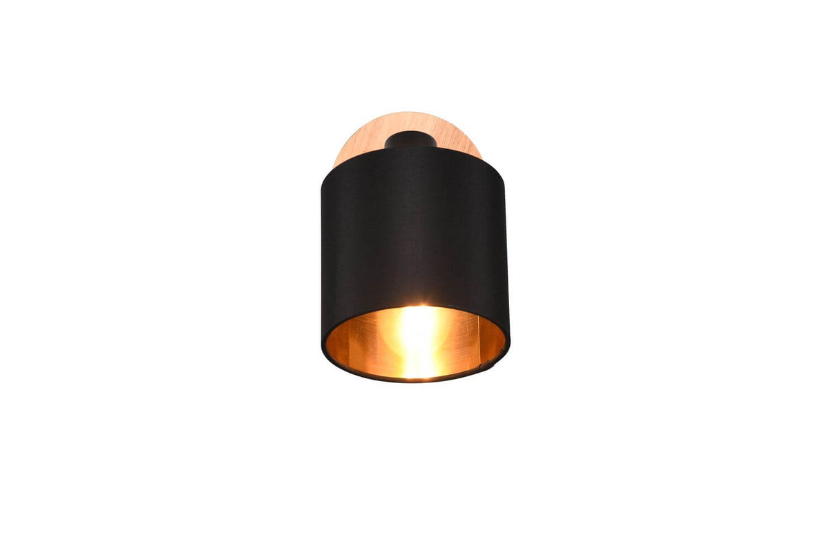 Face avant du spot cylindrique noir, intérieur cuivré lumineux et support en bois.