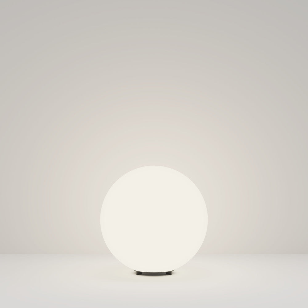 Globe lumineux blanc posé sur un discret socle sombre, vue de face