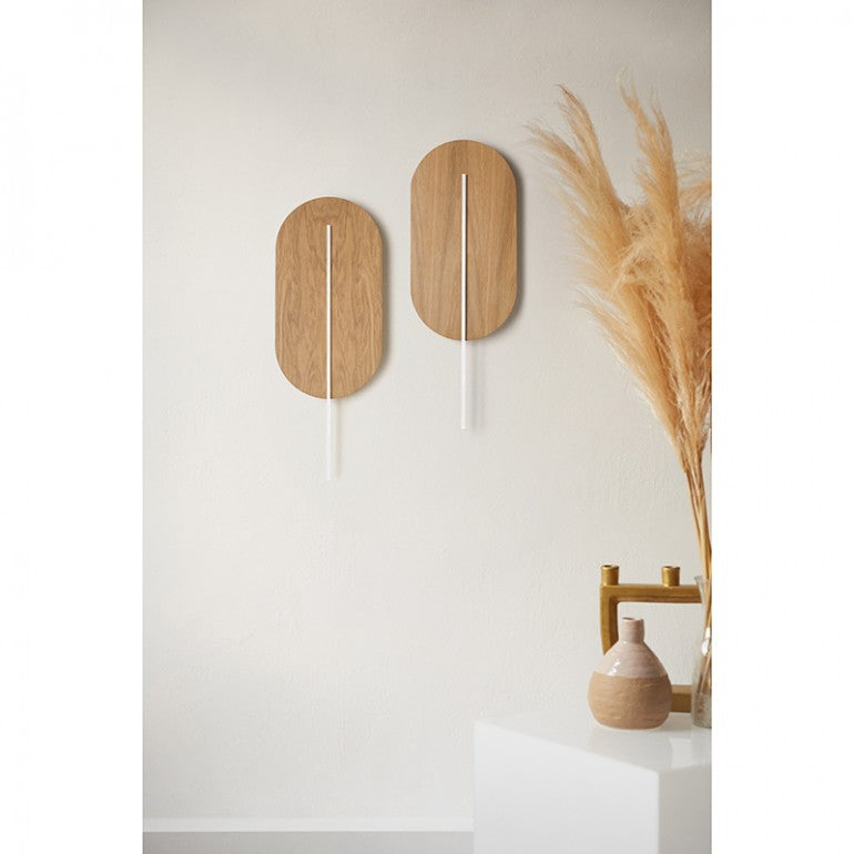 Deux appliques ovales blanches fixées au mur dans un intérieur avec pampas et vase