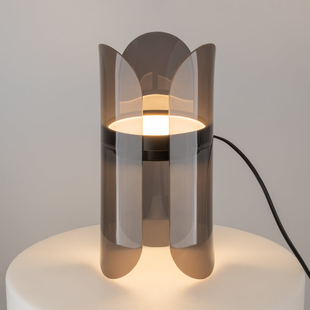 Lampe allumée posée sur socle clair, pétales de verre diffusant lumière chaude