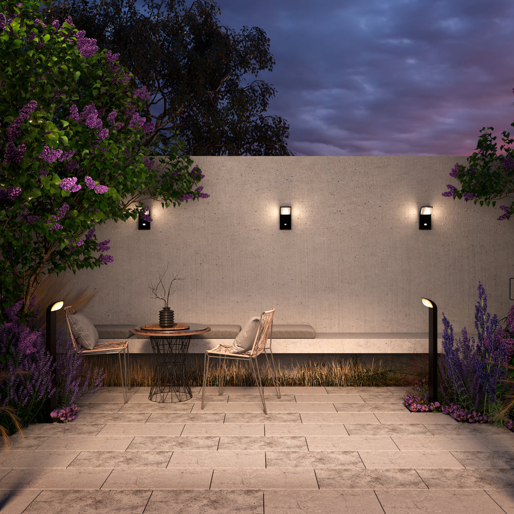 Mise en ambiance nocturne d'une terrasse avec luminaires muraux et bornes éclairées.