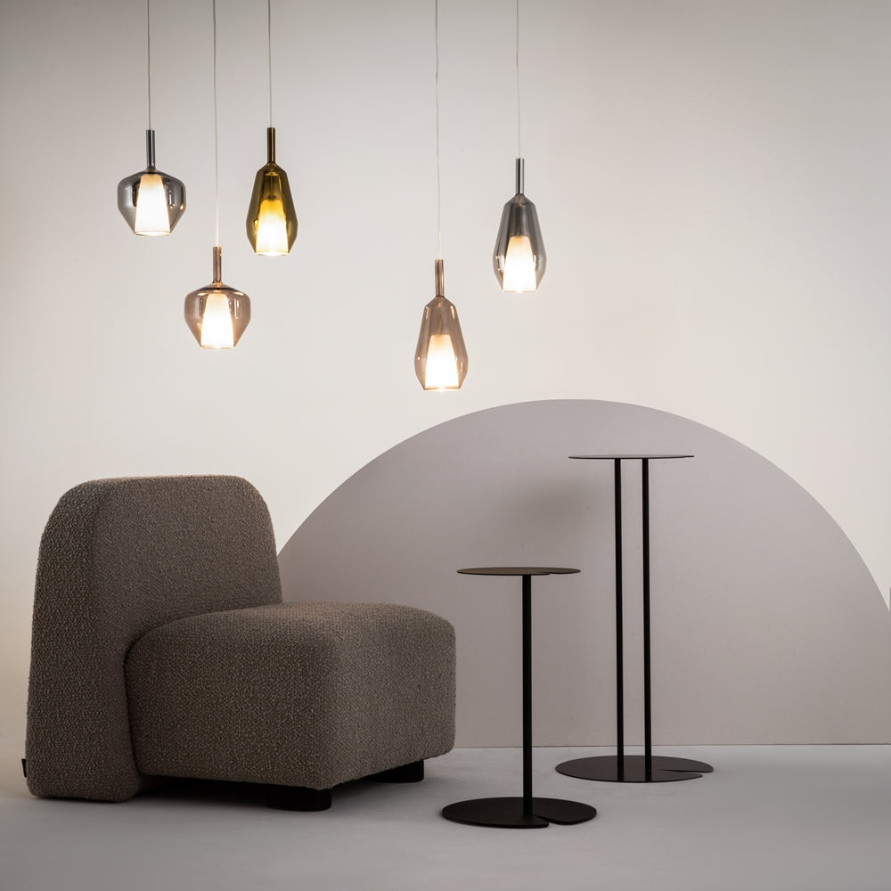 Mise en ambiance avec cinq suspensions colorées au-dessus d'un fauteuil et de tables