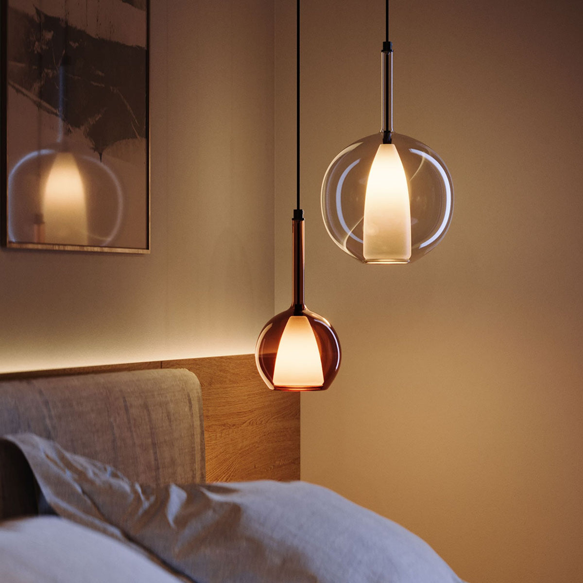 Deux suspensions devant une tête de lit, verre ambré et transparent en gros plan