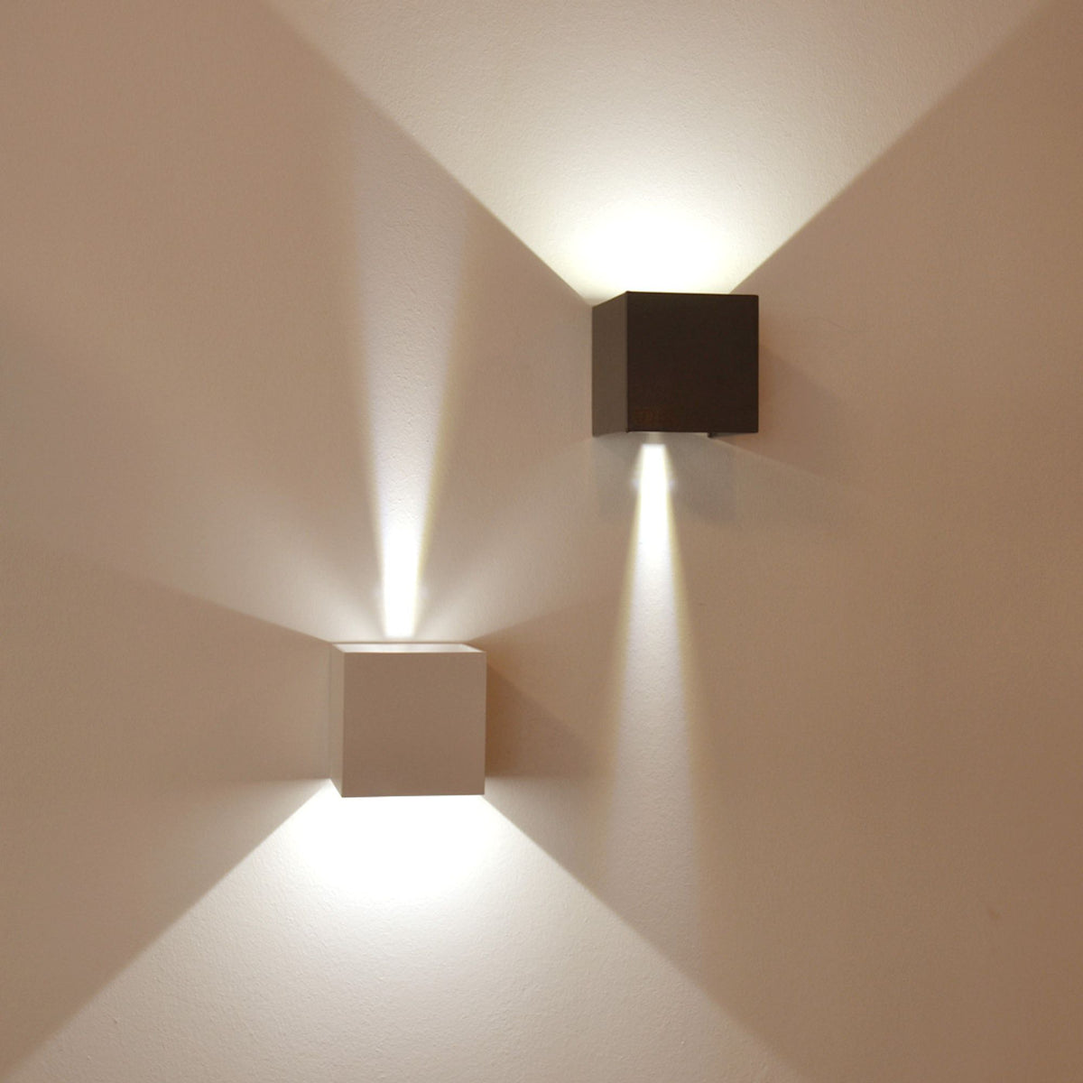 Détail de deux appliques, une blanche et une noire, projetant la lumière vers le haut
