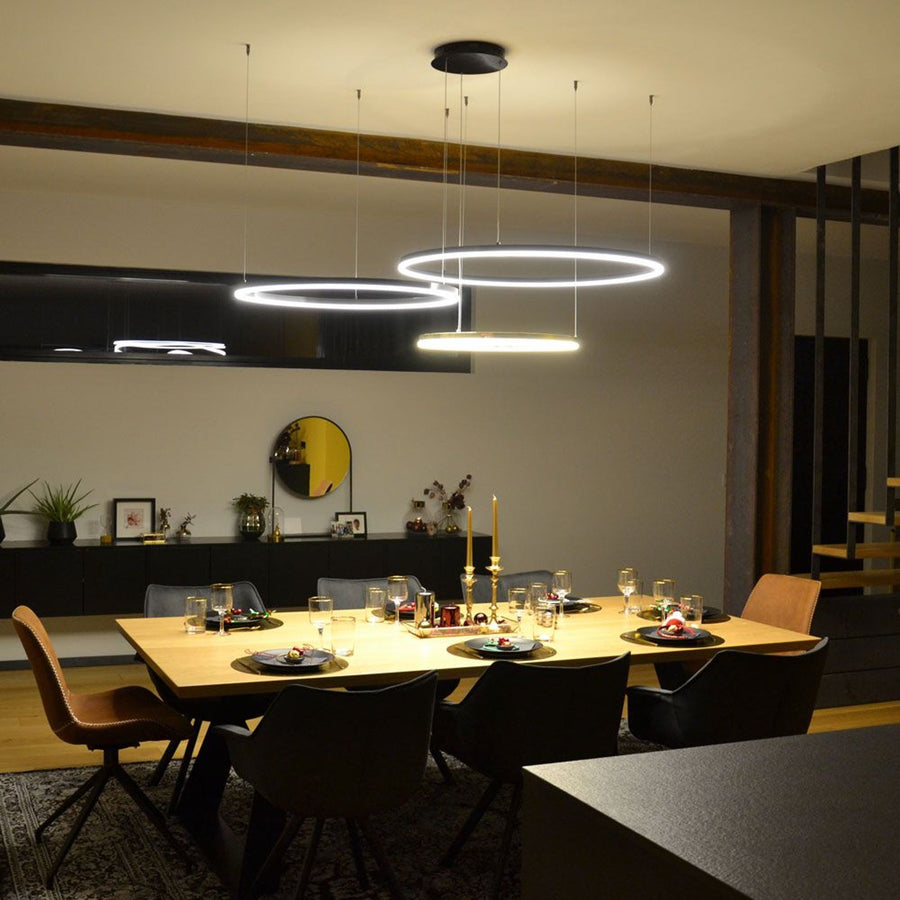 Salle à manger aménagée avec suspension à trois anneaux au-dessus d'une grande table.