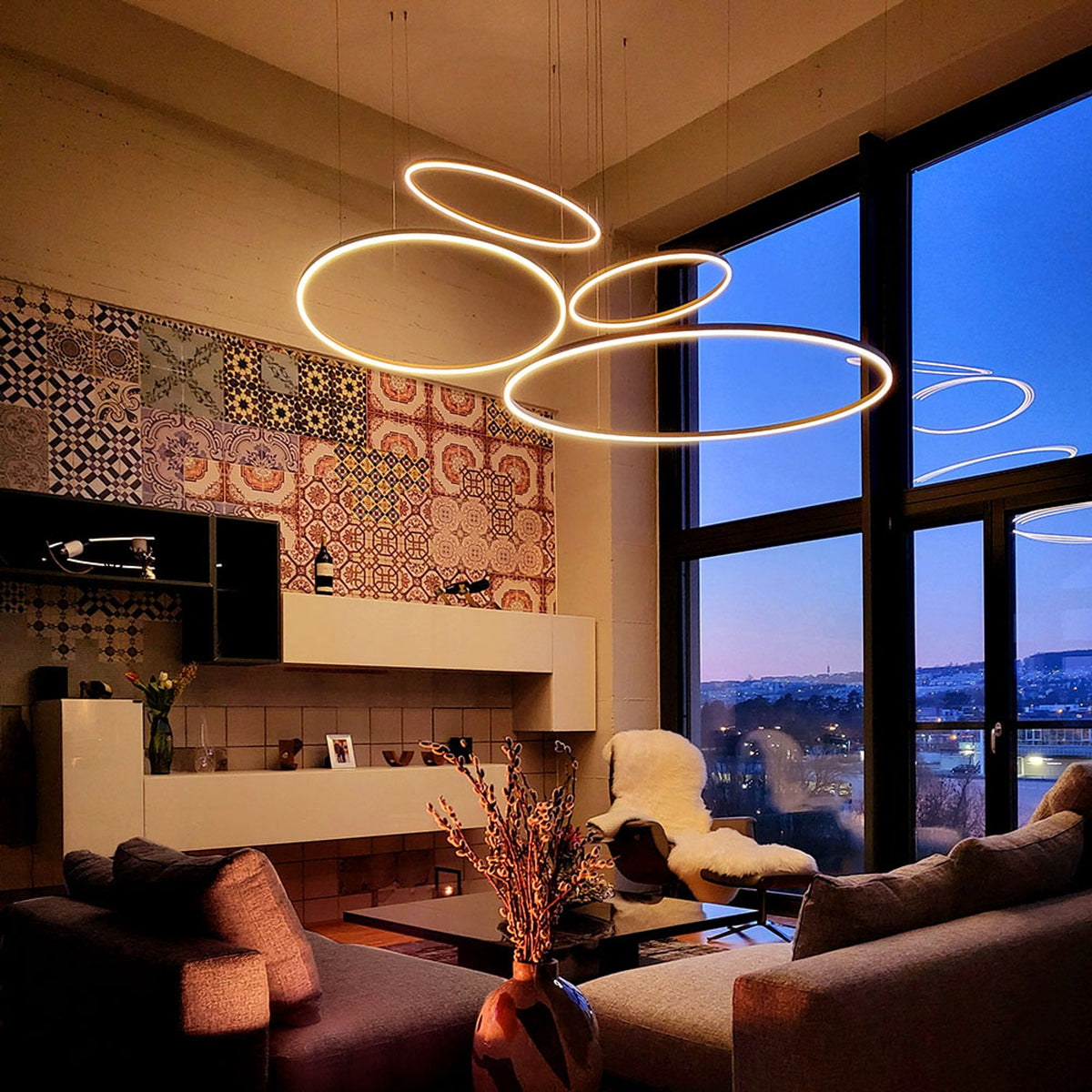 Mise en ambiance le soir, anneaux lumineux devant baie vitrée et vue urbaine
