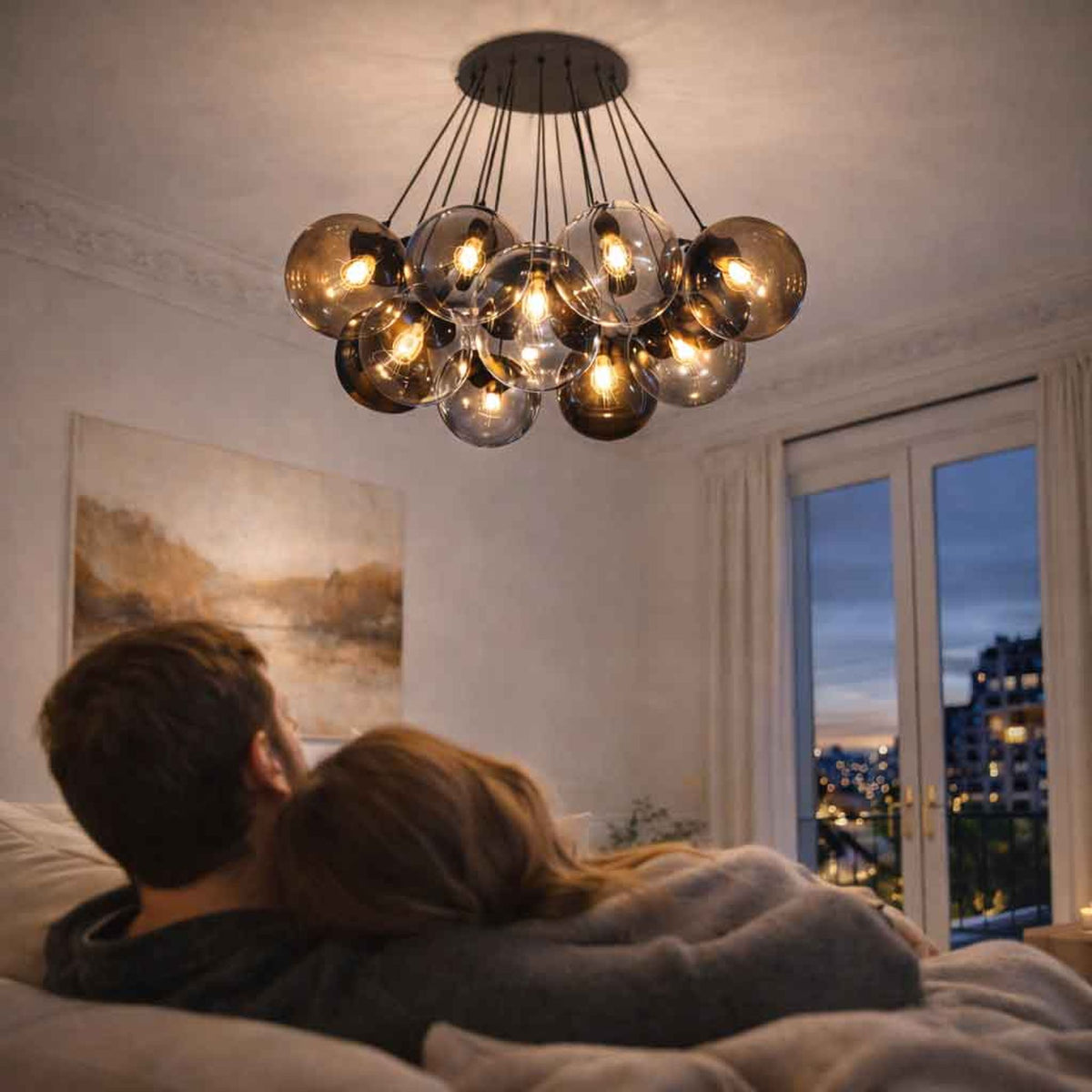 Couple allongé dans une chambre éclairée par une suspension à globes de verre suspendus.