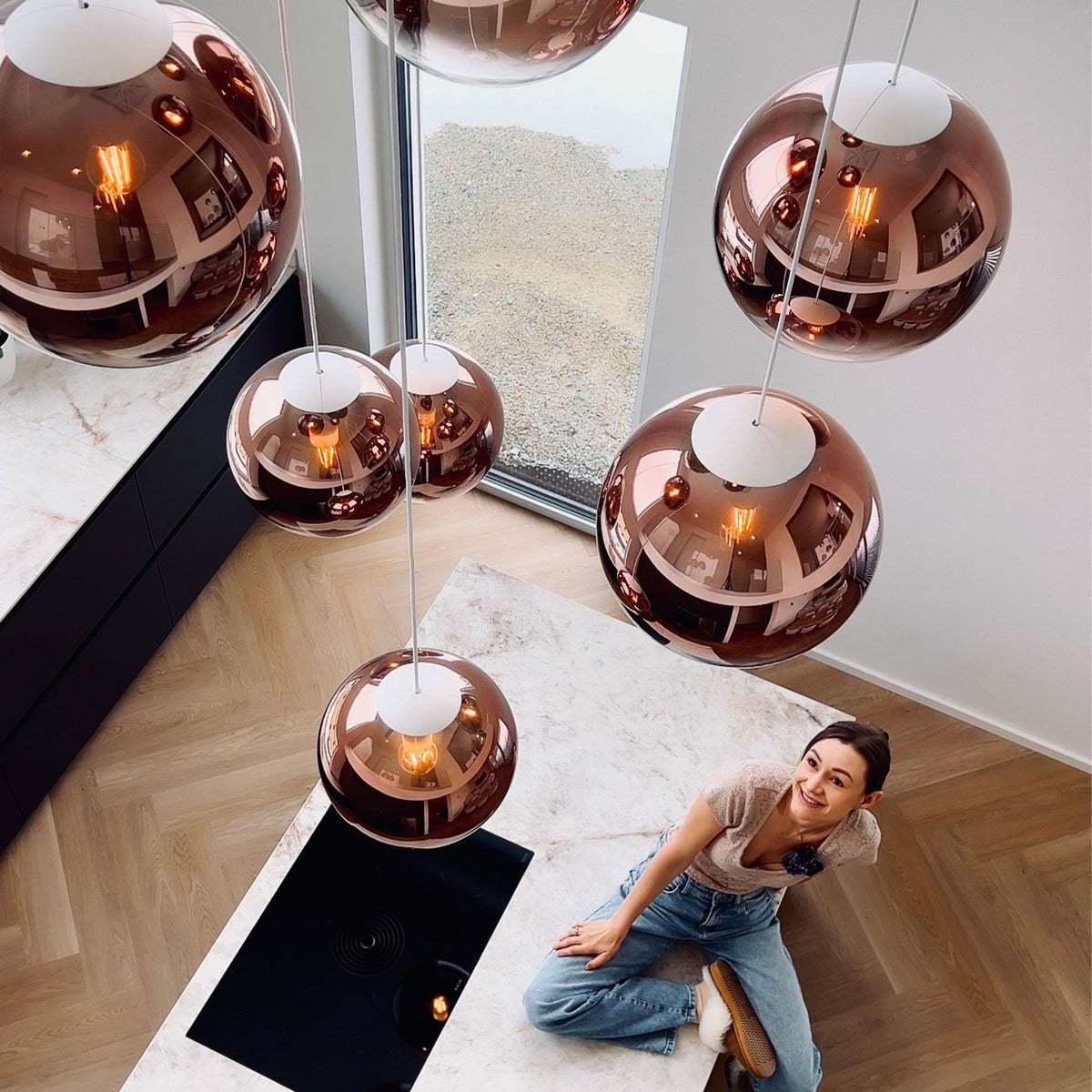 Globes cuivrés réfléchissants vus de dessus, reflets d'intérieur et personne assise