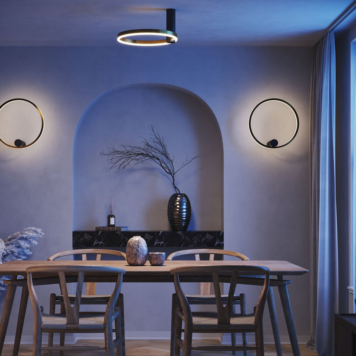 Salle à manger bleutée avec plafonnier et deux appliques anneaux allumés.