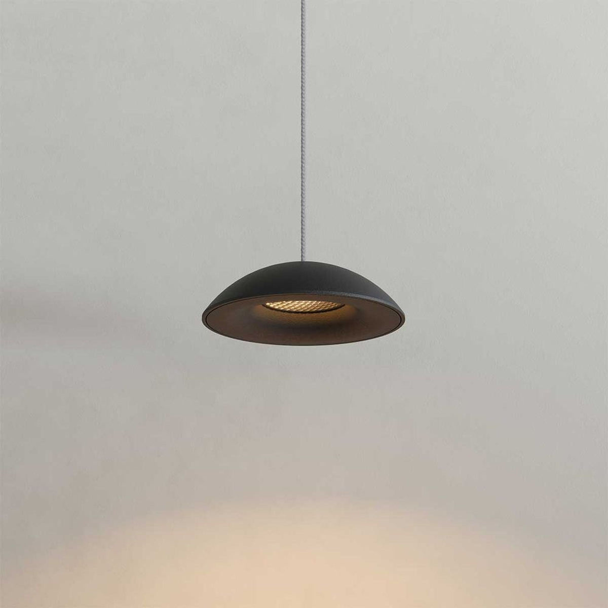 Détail rapproché d'un abat-jour noir bombé diffusant une lumière chaude vers le bas
