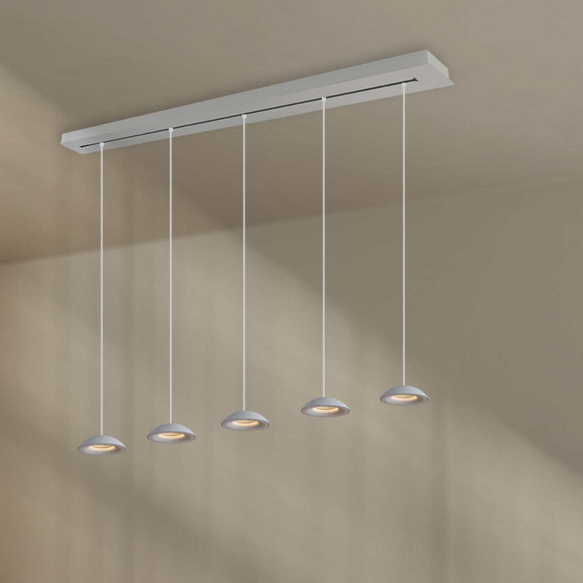 Version blanche du luminaire, barre rectangulaire et cinq suspensions fines depuis le plafond