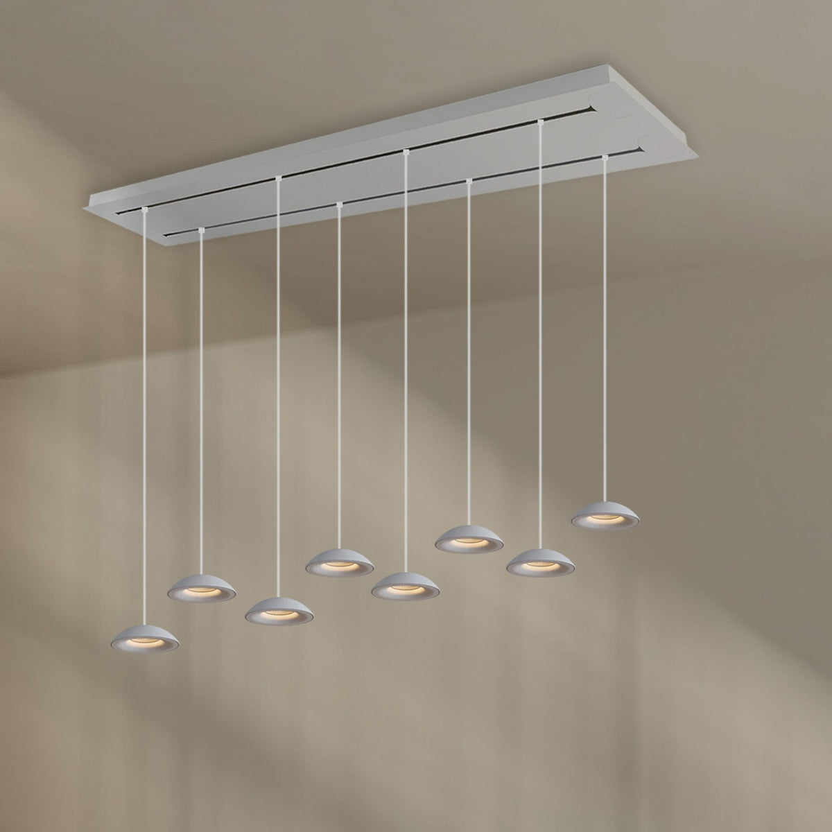 Vue de face du luminaire blanc, huit suspensions fines et coupoles alignées