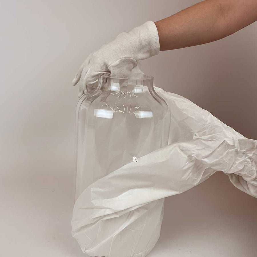 Verre cylindrique transparent déballé avec des gants blancs par une main