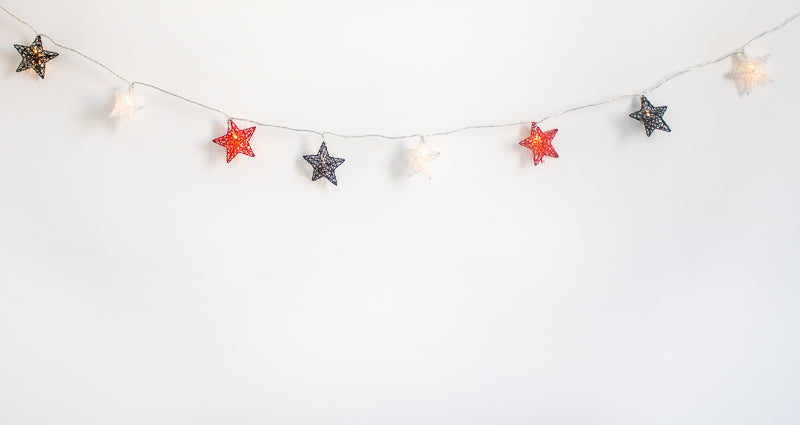 Guirlande d'étoiles multicolores tendue sur fond blanc, étoiles espacées régulièrement