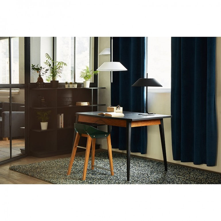 Mise en ambiance : suspensions blanche et noire au-dessus d'un bureau en bois