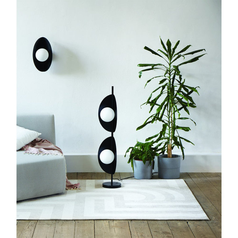 Mise en ambiance salon avec lampadaire noir près d'une grande plante verte