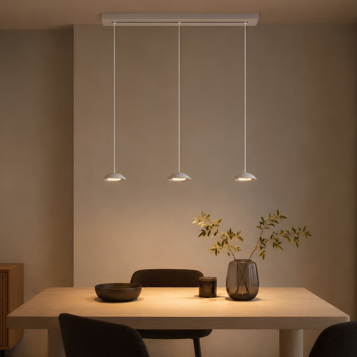 Suspension trois lumières éclairant une table à manger en bois clair