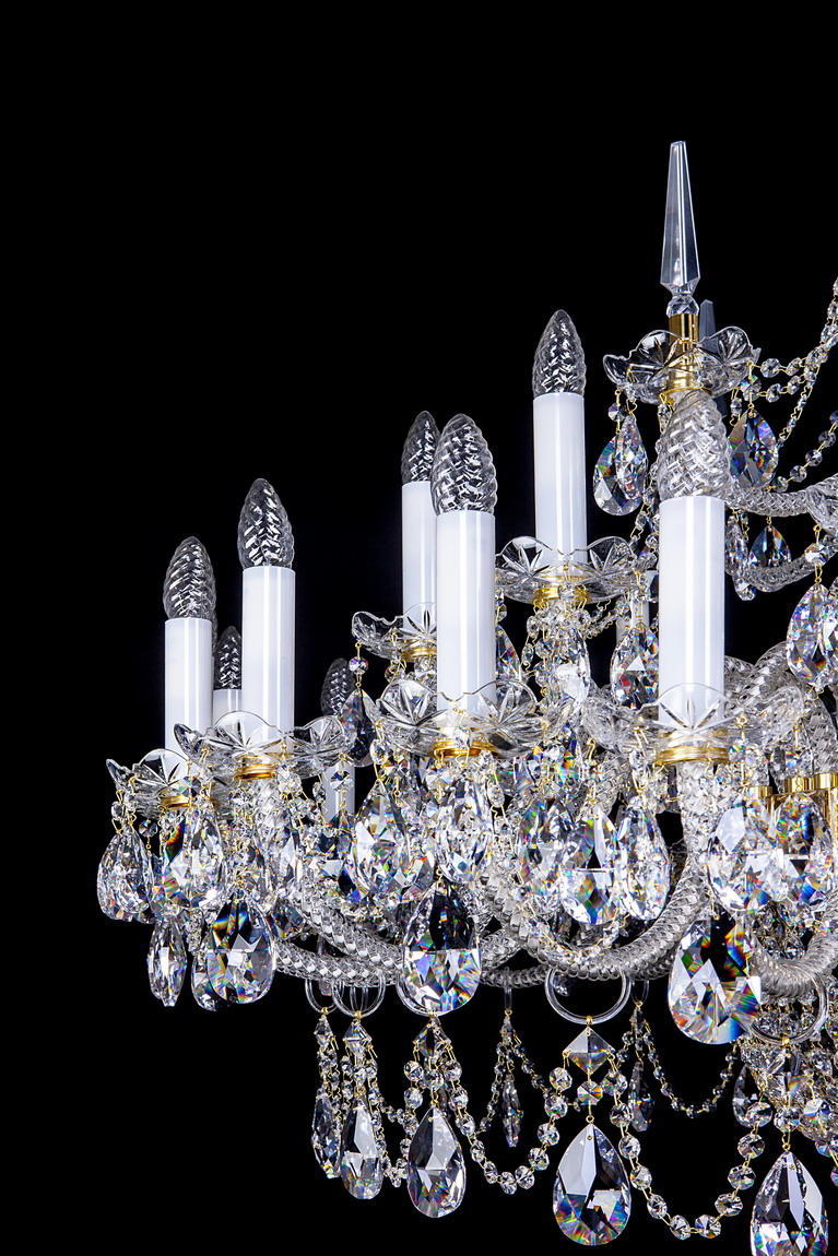 Détail des bras dorés, bougies blanches et pendeloques de cristal taillé