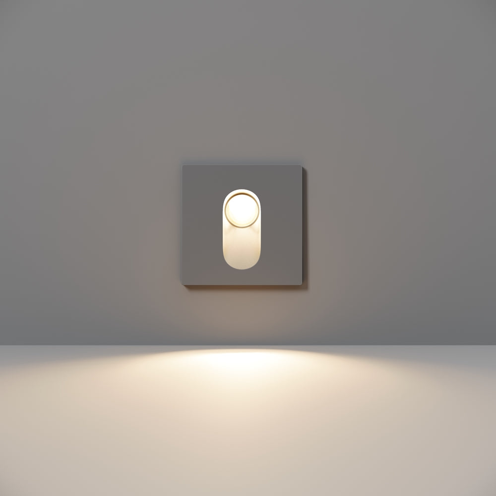 Vue de face du luminaire allumé, anneau clair autour de l'ouverture ovale.