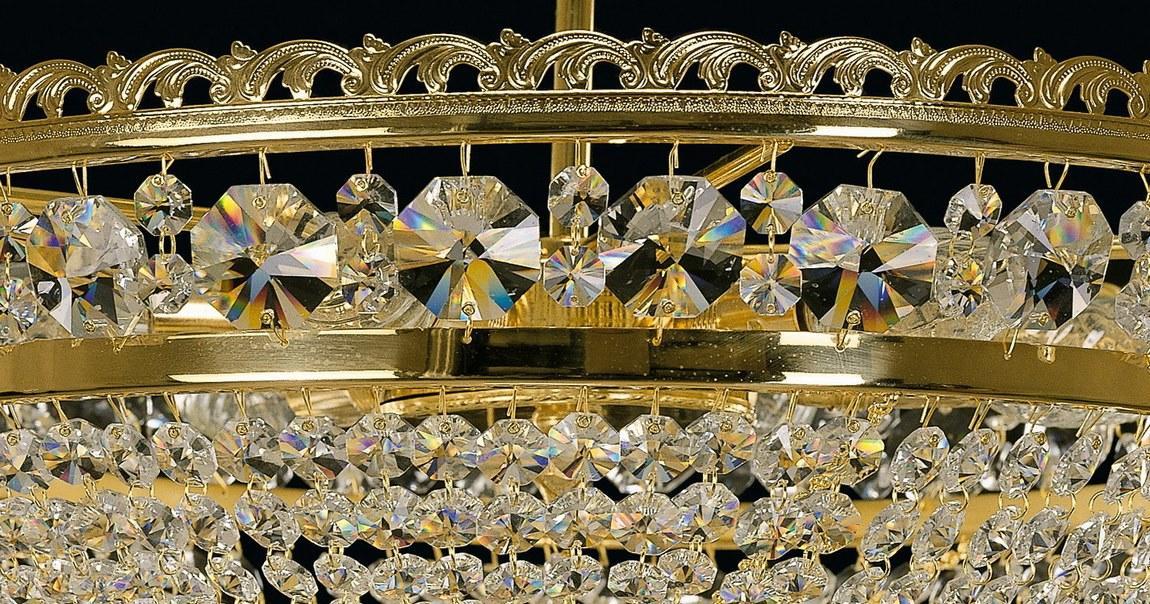 Gros plan sur la couronne dorée et les cristaux suspendus du plafonnier