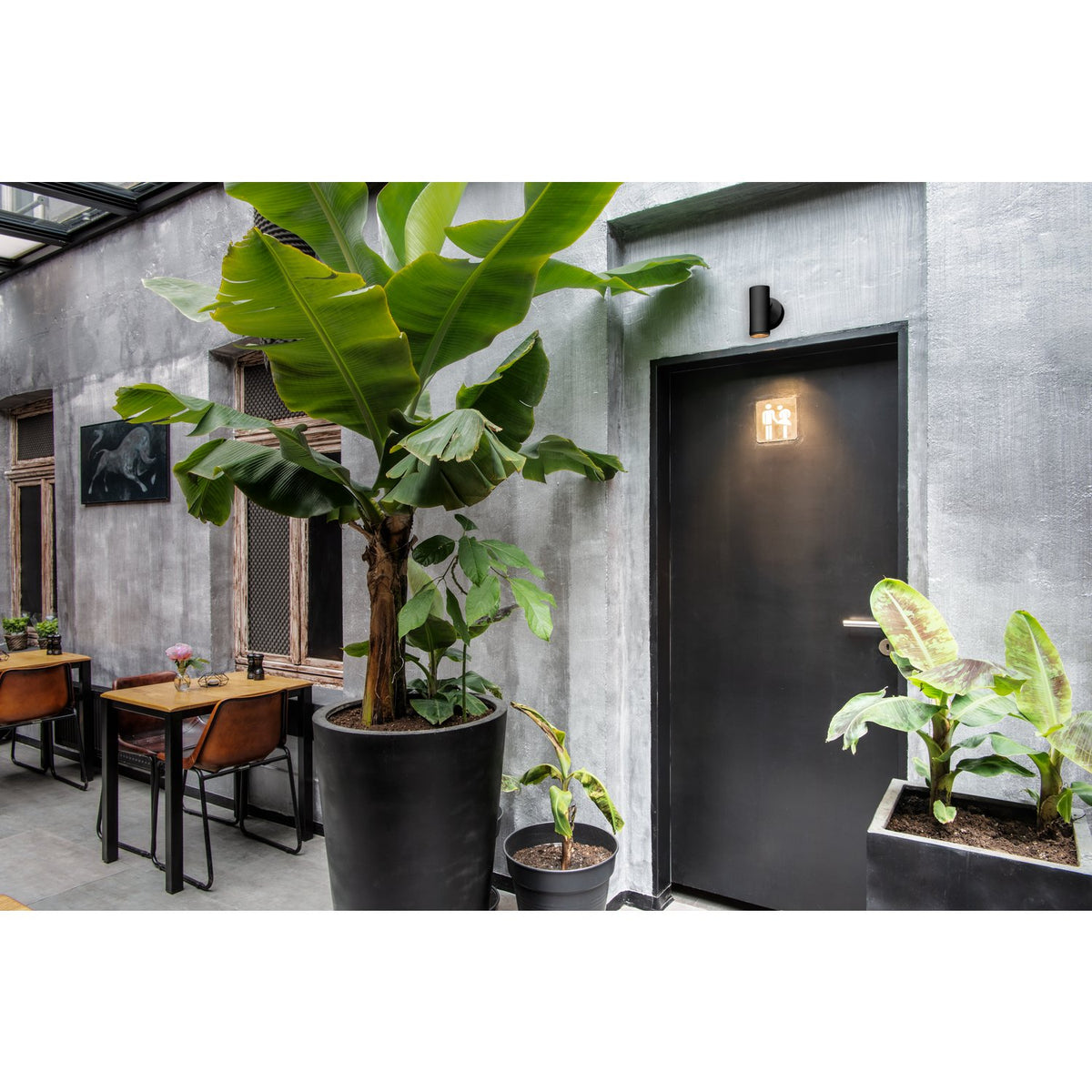 Mise en ambiance : spot noir allumé au-dessus d'une porte de toilettes.