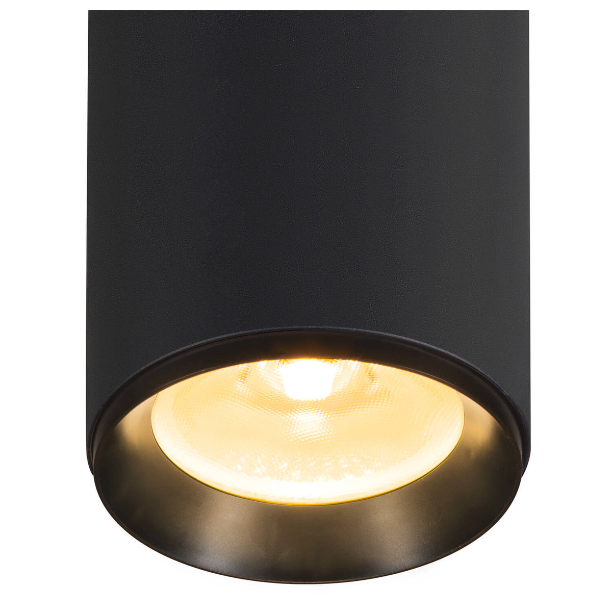 Gros plan du bas du luminaire allumé, diffuseur chaud et réflecteur interne doré.