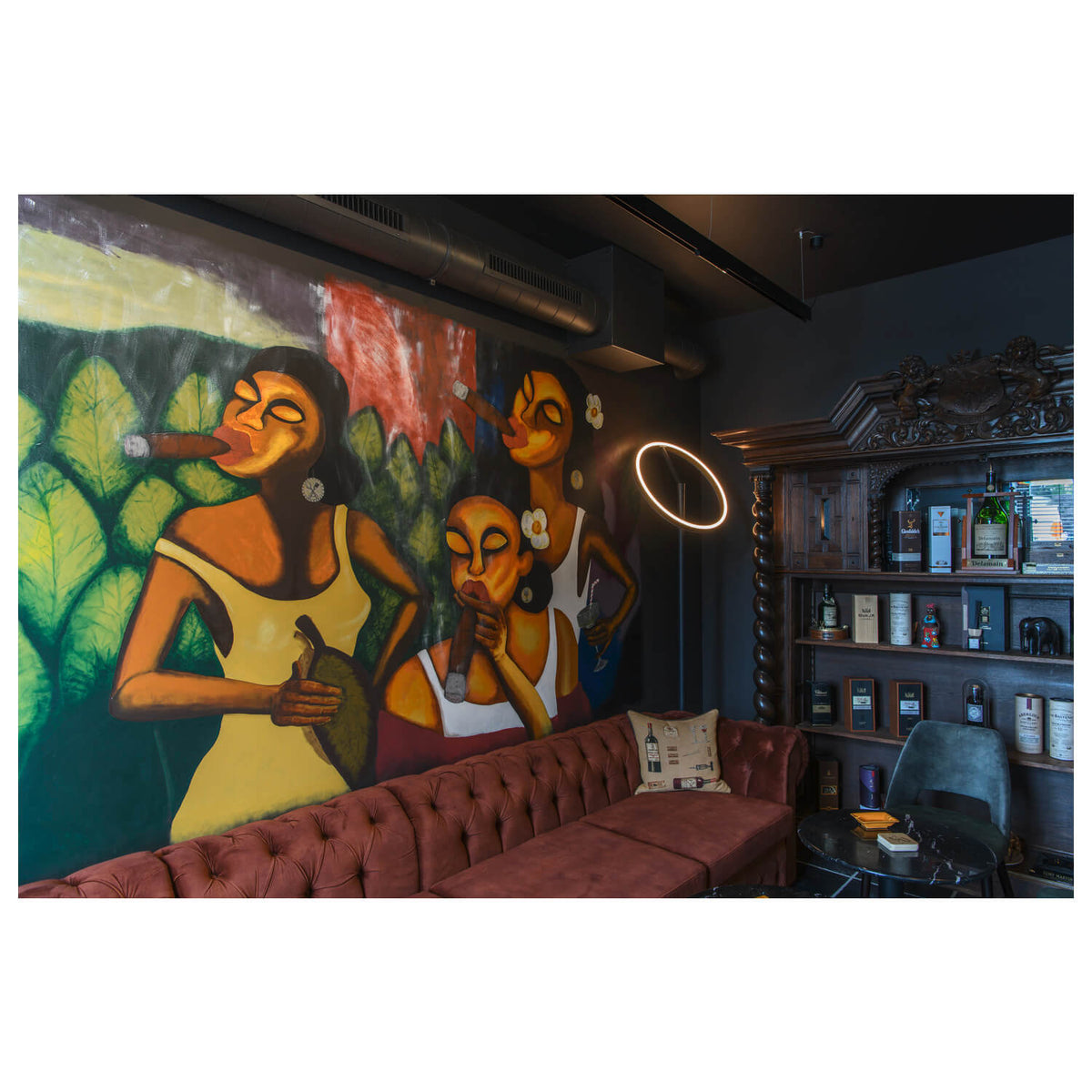 Mise en ambiance dans un bar : lampadaire allumé devant une grande fresque colorée et une banquette.