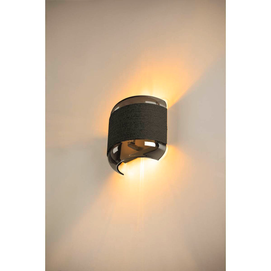 Applique allumée sur mur beige diffusant un halo lumineux vers le haut et le bas