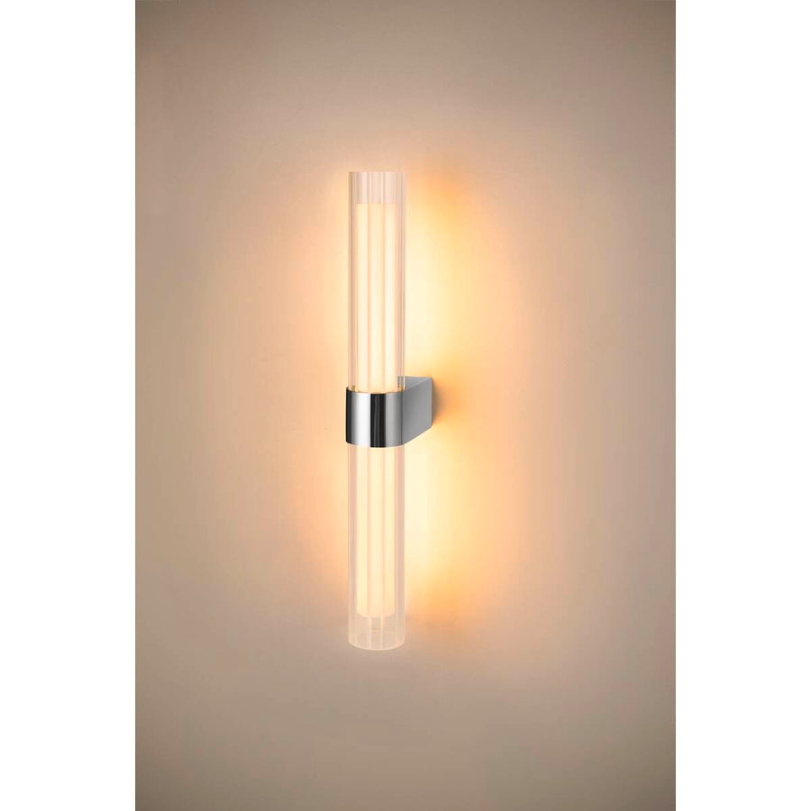 Applique allumée sur mur beige, halo lumineux chaud et reflet doux.