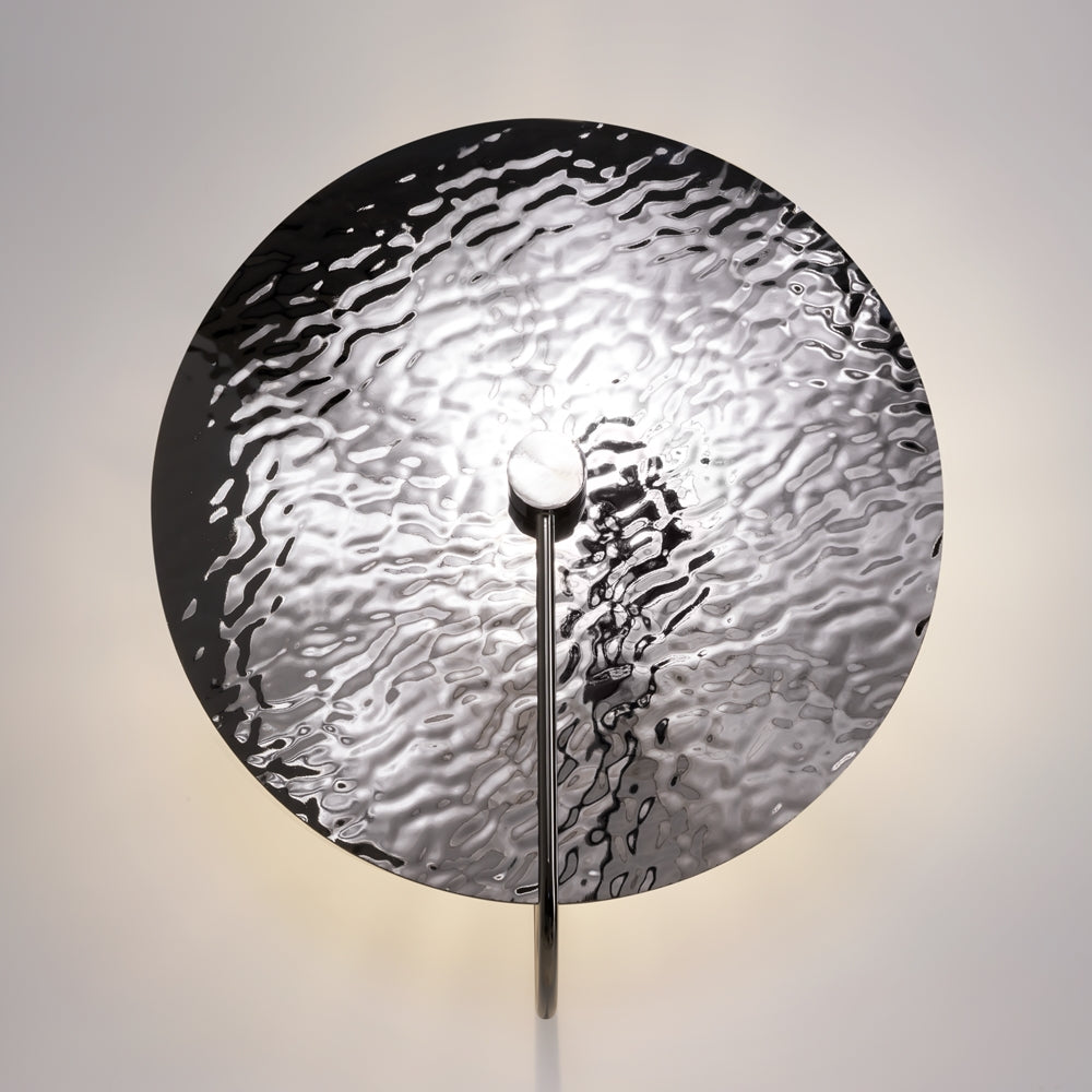 Applique ronde éclairée fixée au mur, halo lumineux diffus autour du disque