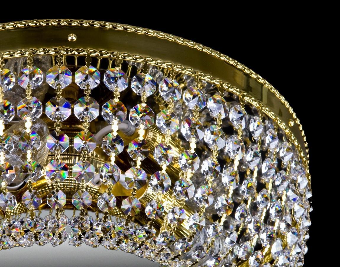 Plan serré sur la frise perlée dorée et les pendentifs de cristal