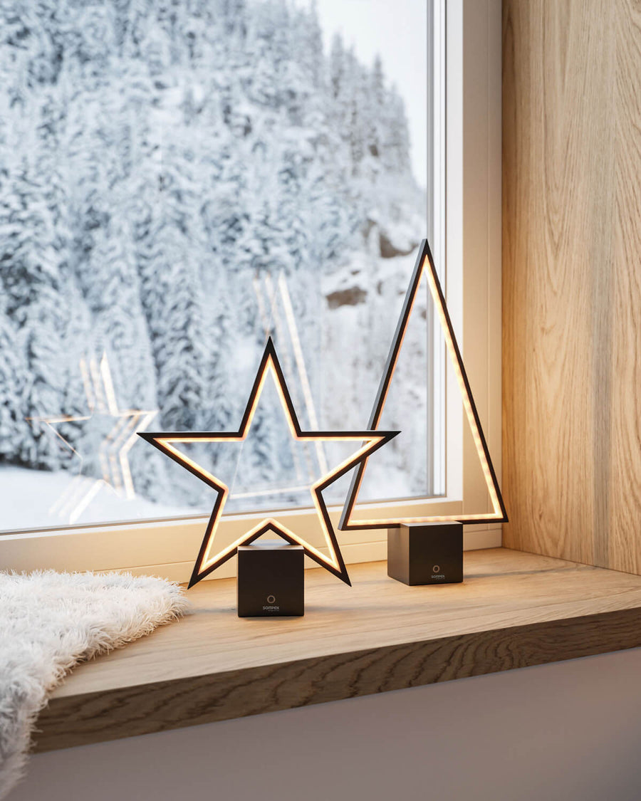 Deux lampes étoile et sapin posées sur rebord de fenêtre, paysage de neige.