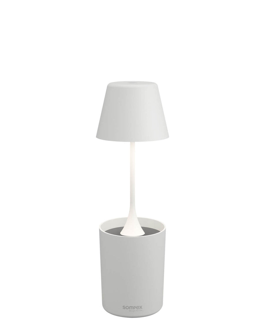 Lampe blanche de face sur fond blanc, abat-jour conique et socle cylindrique.