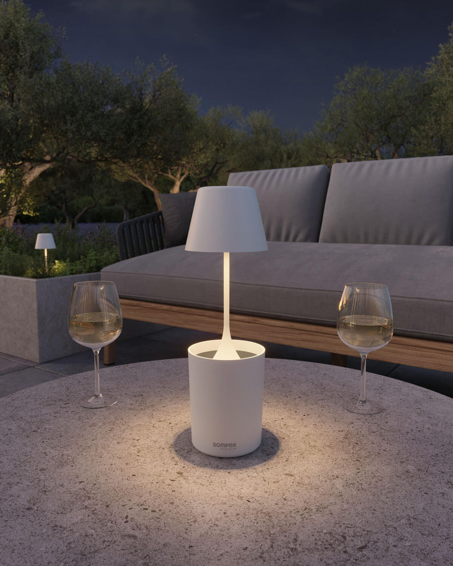 Gros plan de la lampe allumée sur une table, entourée de deux verres.