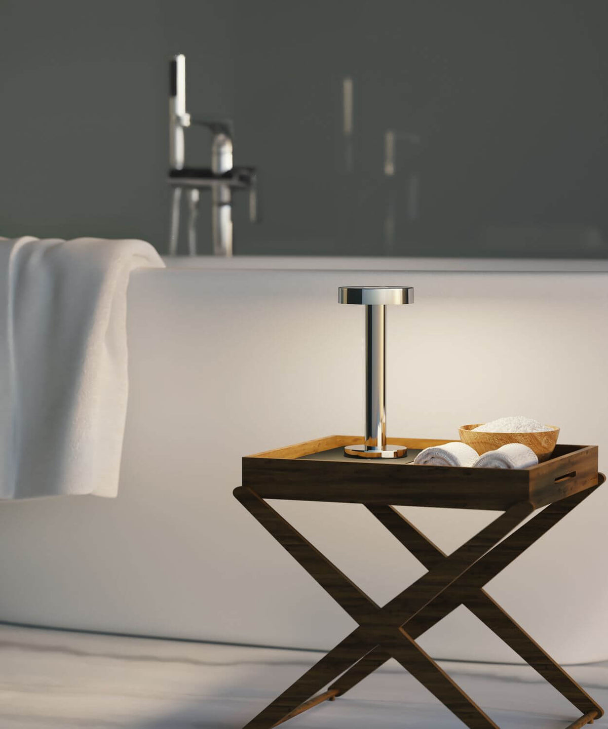 Lampe chromée posée sur un plateau en bois près d'une baignoire, ambiance salle de bain.
