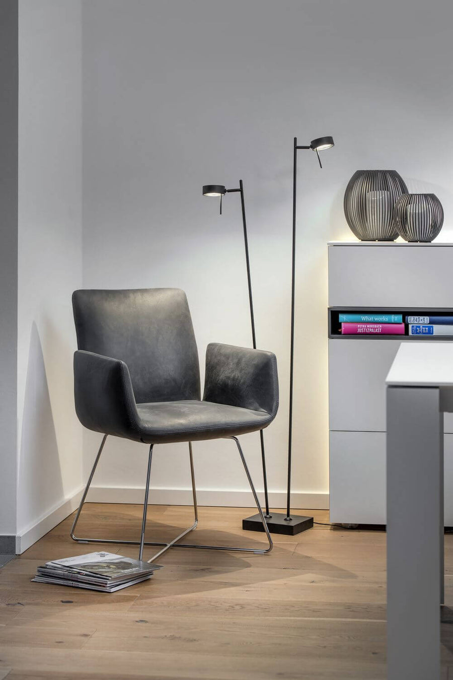 Lampadaire noir installé dans un salon moderne près d'un fauteuil et d'un meuble