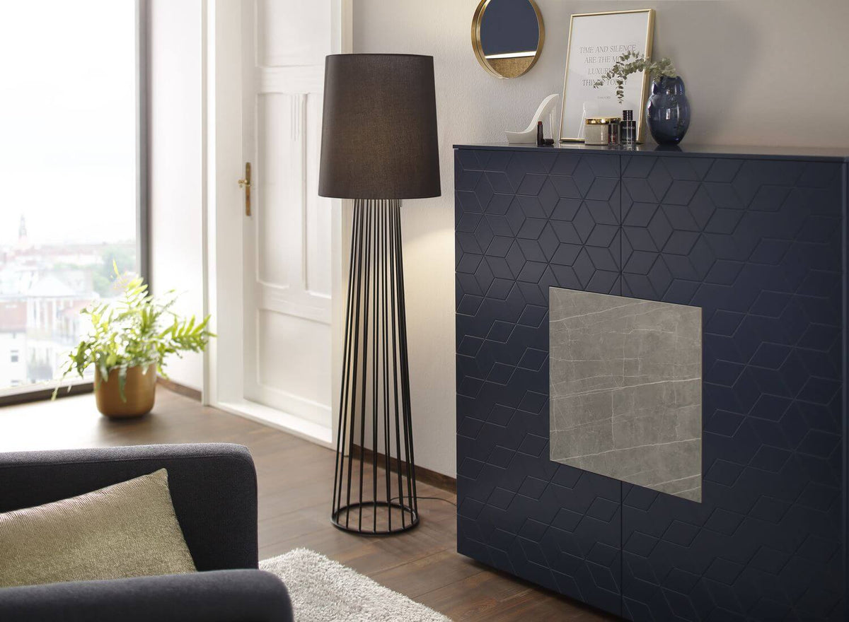 Lampadaire noir allumé dans un salon, près d'un meuble bleu et d'une fenêtre