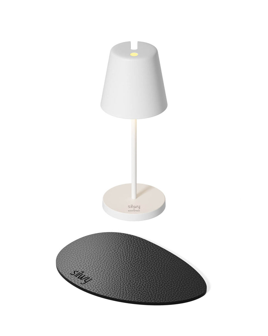 Lampe blanche à poser avec socle rond et pastille noire texturée.