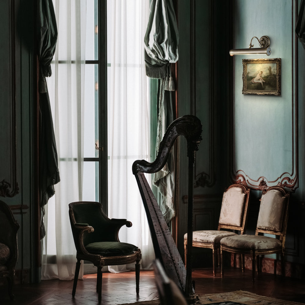Mise en ambiance intérieure avec applique murale éclairant un tableau au-dessus d'une harpe.