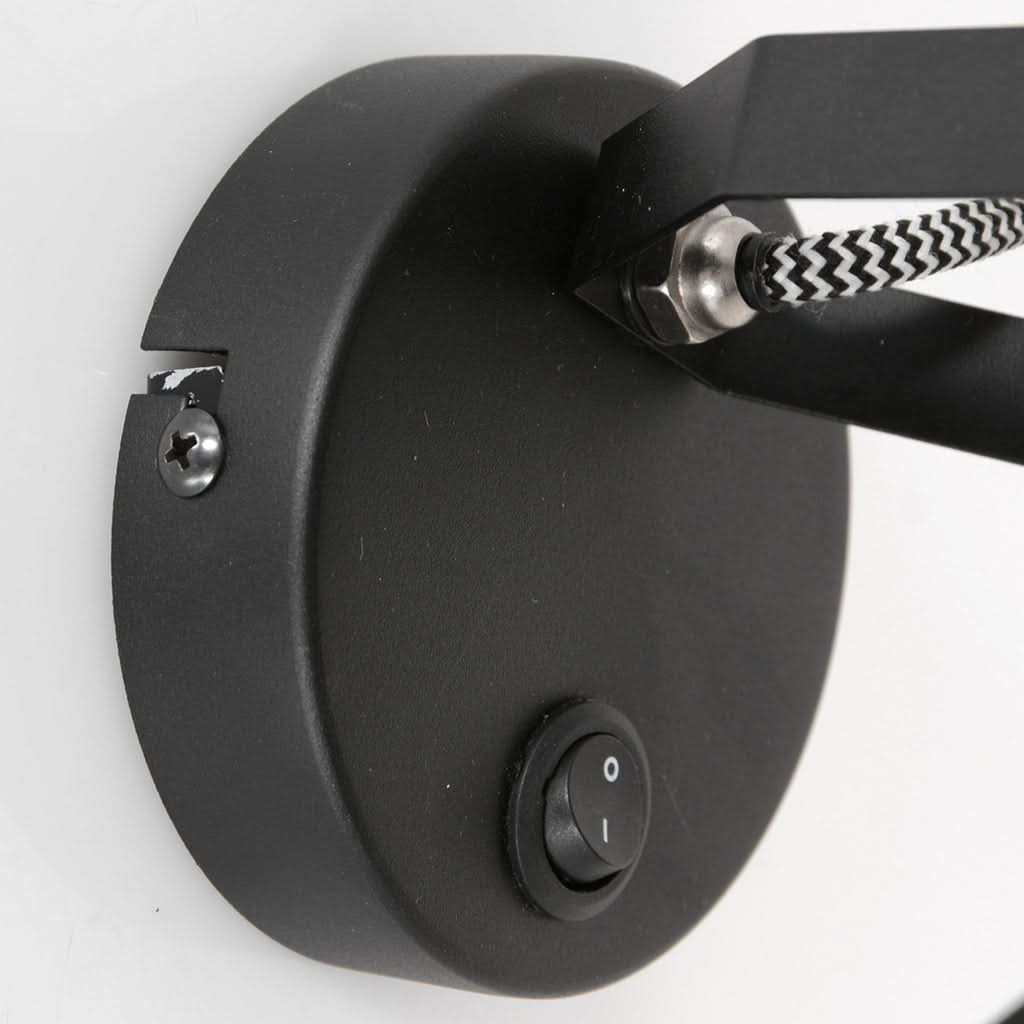 Détail de la platine murale noire avec interrupteur basculant, vis de fixation et câble tressé.