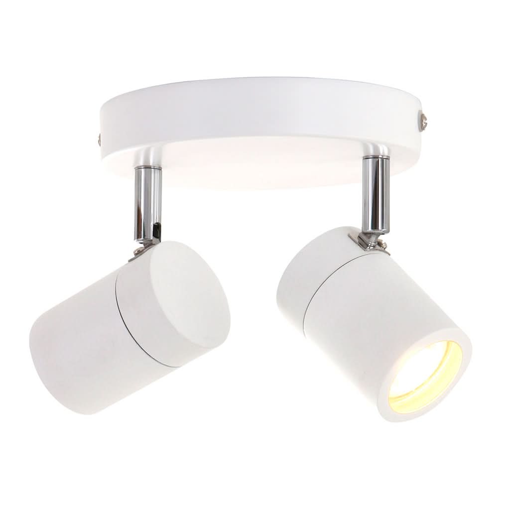 Vue de face du luminaire blanc à deux projecteurs cylindriques inclinés, lumière allumée