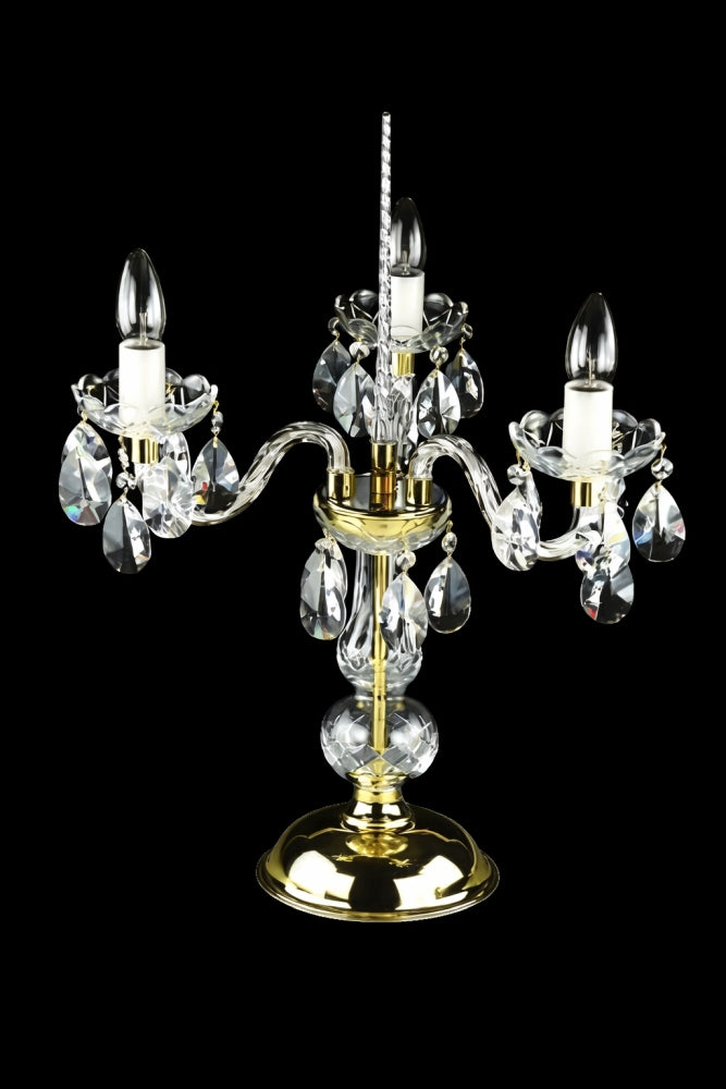 Version dorée de la lampe, ampoules éteintes, bras recourbés et pampilles transparentes.