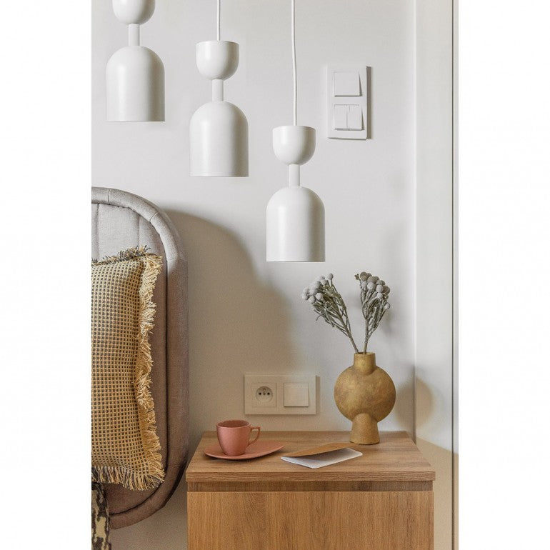 Mise en ambiance chambre : trois suspensions blanches au-dessus d'une table de chevet en bois