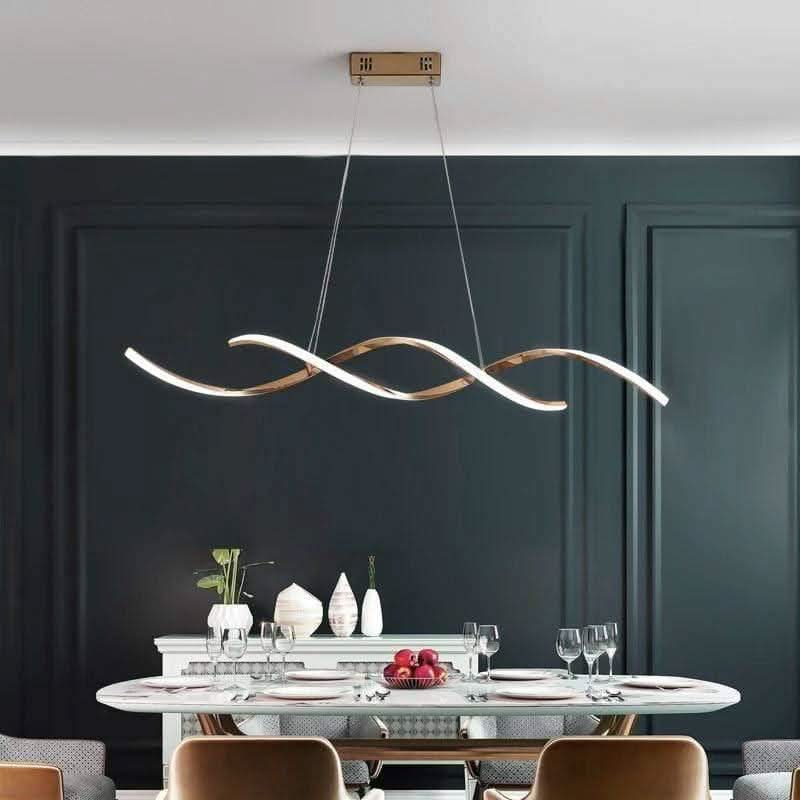 Vue de face du luminaire doré sur mur noir, grande table dressée de plats