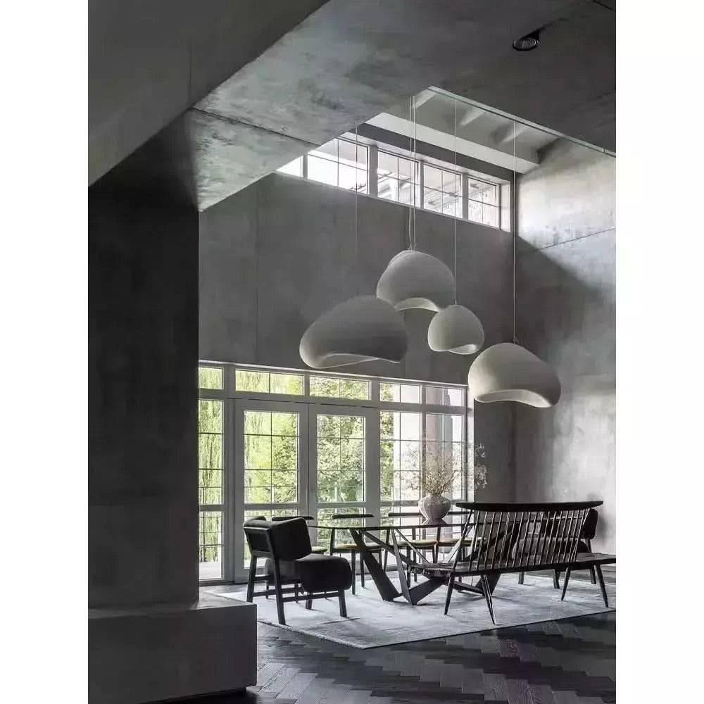 Quatre suspensions blanc mat flottant dans un volume béton brut très lumineux