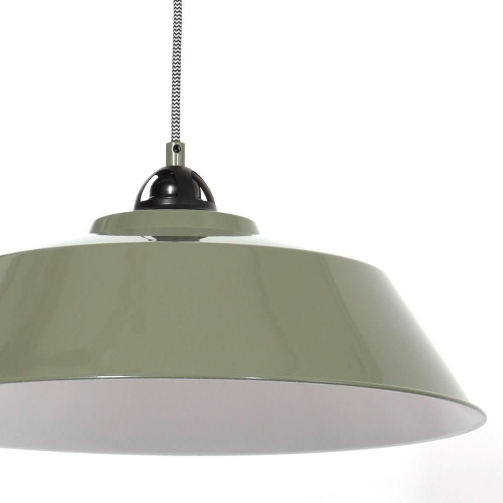 Détail rapproché de l'abat-jour vert et de sa fixation noire, intérieur blanc.