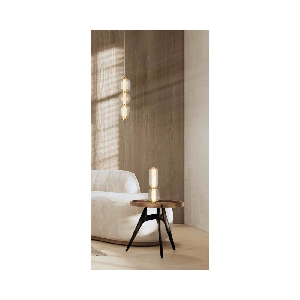 Suspension allumée au-dessus d'une petite table ronde, près d'un canapé blanc.