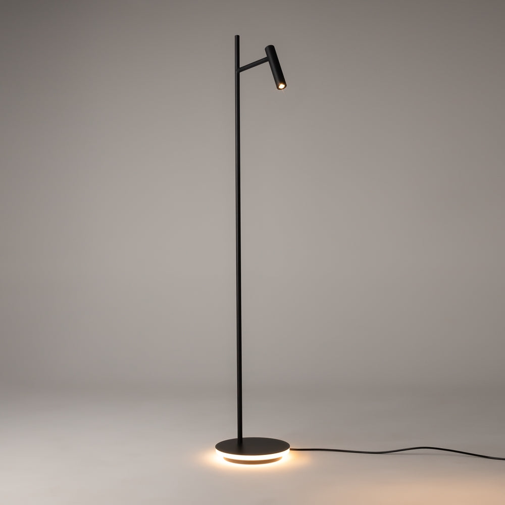 Lampadaire noir allumé sur fond gris, projecteur orienté vers le bas, halo lumineux sous la base.