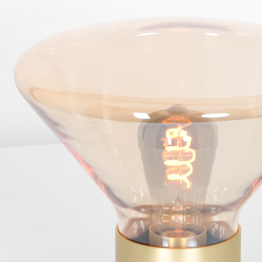 Gros plan sur l'abat-jour en verre ambré et la spirale lumineuse de l'ampoule.
